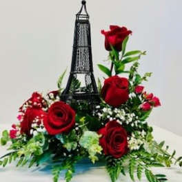 Red roses arranged around a small Eiffel Tower decoration