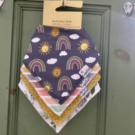 Stack of patterned baby bandana bibs hanging on a hook