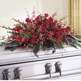 Red floral casket spray with roses and dark ribbon