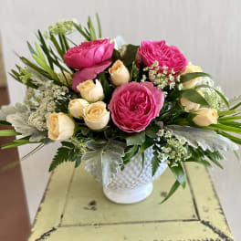 Pink and cream roses arranged in a white vase