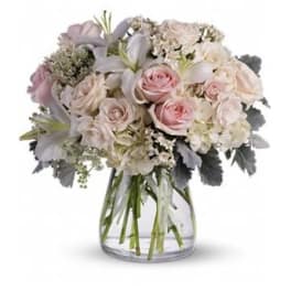 Bouquet of pale pink roses and white lilies in a clear glass vase