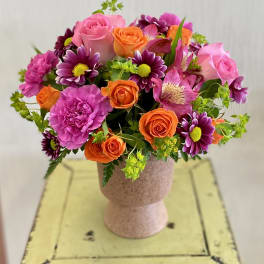Bouquet of pink, orange, and purple flowers in a pedestal vase
