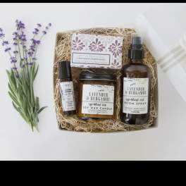 Lavender sprigs beside a gift box with soap, candle, and room spray