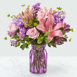 Pink lilies and roses in a purple glass vase