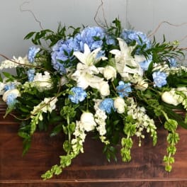 Large blue and white floral arrangement on a wooden casket