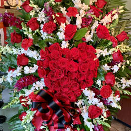 Large red rose and orchid standing spray with a black-and-red ribbon bow