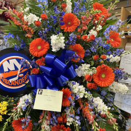 Large sympathy spray with orange gerberas, blue flowers, and white blooms
