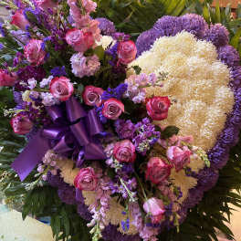 Large purple and pink floral standing arrangement with a ribbon bow