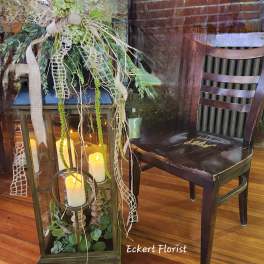 Lantern centerpiece with candles and trailing greenery on a wooden floor