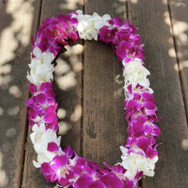 Pink and white orchid lei on a wooden surface