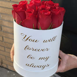 Red roses in a white round box with gold text