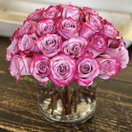 Tightly clustered pink roses arranged in a round dome in a clear glass vase