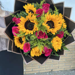 Bouquet of yellow sunflowers and hot pink roses wrapped in black paper