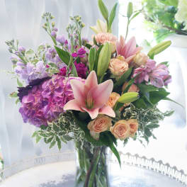 Pink lilies and roses arranged in a glass vase