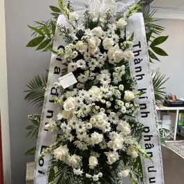 Large white funeral standing spray with roses and daisies on a ribboned easel