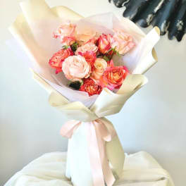 Bouquet of pink and peach roses wrapped in cream paper