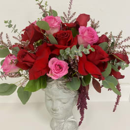 Arrangement of red and pink roses in a gray head-shaped vase