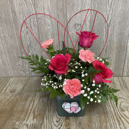 Pink and red roses with carnations in a square vase