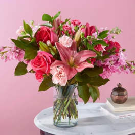 Pink roses and lilies arranged in a clear glass vase