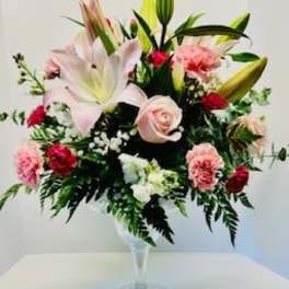 Pink lilies and roses arranged in a clear glass vase