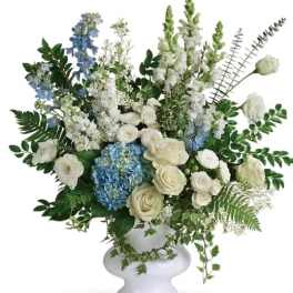 White and blue floral arrangement in a white pedestal vase