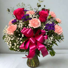 Bouquet of pink roses and carnations with purple filler in a glass vase