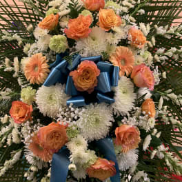 Orange roses and white daisies arranged with a blue ribbon bow