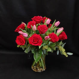 Bouquet of red roses and pink tulips in a glass vase