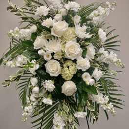 White floral standing spray with roses and carnations on an easel