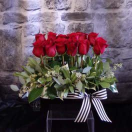 Red roses arranged in a black box with a striped ribbon