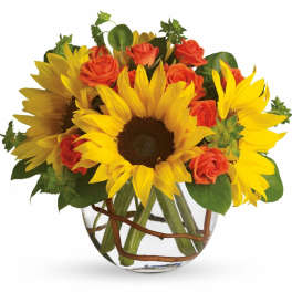 Sunflowers and orange roses arranged in a clear glass vase