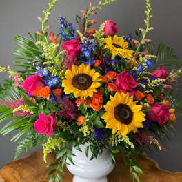 Bright mixed bouquet with sunflowers and pink roses in a white vase