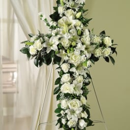 White floral cross arrangement on a stand