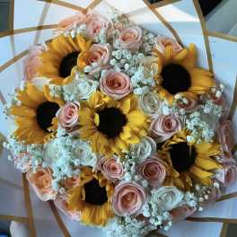 Bouquet of sunflowers and pastel roses wrapped in white paper