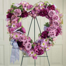 Heart-shaped floral wreath with pink and purple flowers on a stand