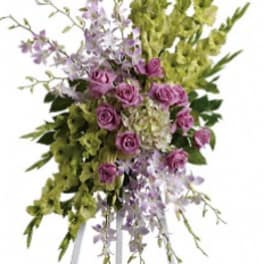 Standing floral spray with purple roses and green orchids on an easel