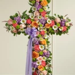 Cross-shaped floral standing spray with a purple ribbon