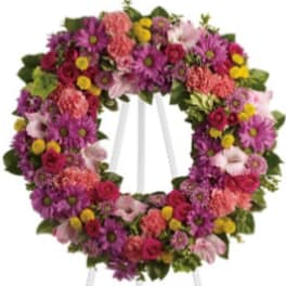 Heart-shaped floral wreath on a white easel with pink, purple, and yellow flowers
