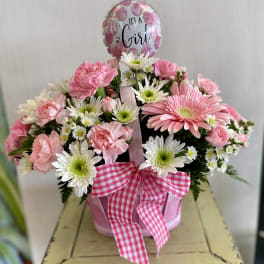 Pink and white flower arrangement in a pink container with a "It's a Girl" balloon