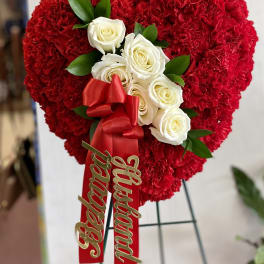 Heart-shaped red carnation arrangement with white roses and a red ribbon