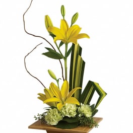 Yellow lilies arranged in a wooden vase with green accents