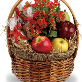 Gift basket with red flowers, apples, pears, and wrapped nuts