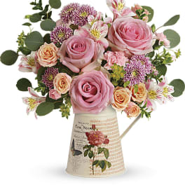 Pink and peach roses with alstroemeria in a decorative pitcher vase