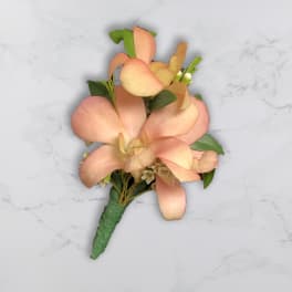 Peach orchid boutonniere with green leaves