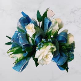 White roses with blue ribbon loops and green leaves in a bouquet