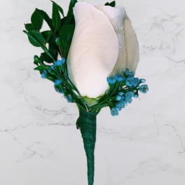 White rose boutonniere with blue accents and green leaves