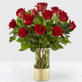 Red roses arranged in a clear glass vase with a gold base