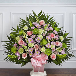 Standing floral spray with pink roses and daisies on a white easel