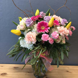 Mixed bouquet of pink, lavender, and yellow flowers in a glass vase