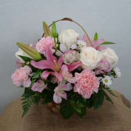 Basket arrangement of pink lilies, white roses, and carnations